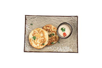 Pancakes with sour cream and chili pepper on grey plate isolated on white background