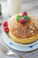 closeup of stacked pancakes raspberries mint sugar milk