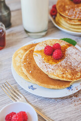 breakfast table with pancakes raspberries mint sugar on white plate