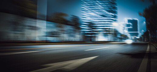 Fototapeta na wymiar At night, wide motion blurred roads on the side of urban high-rise buildings