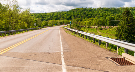 A highway through the woods in Warren County, Pennsylvania, USA on a sunny spring day