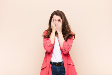young pretty woman feeling scared or embarrassed, peeking or spying with eyes half-covered with...