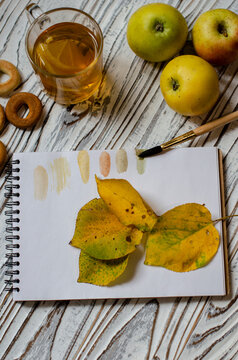 notebook for drawing with autumn leaves and a cup of tea with lemon