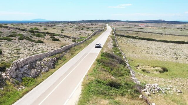 Scenic road on the island of Pag in Croatia, car drive between old agriculture fields and stone drywals
