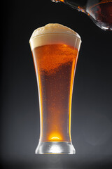 Beer pouring into glass on black background