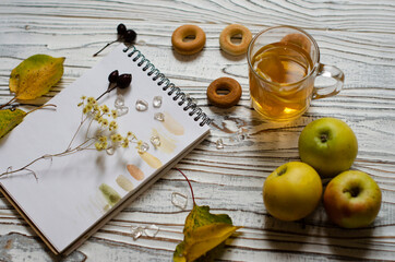 notebook for drawing with autumn leaves and a cup of tea with lemon