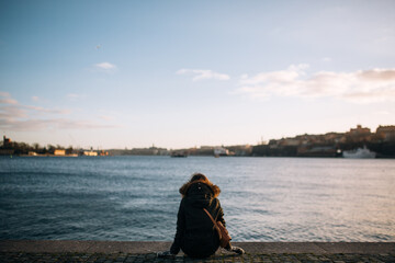 a girl in a winter jacket sits on the background of the frozen sea