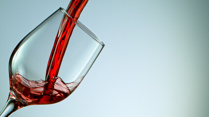 red wine pouring into wine glass isolated on grey background