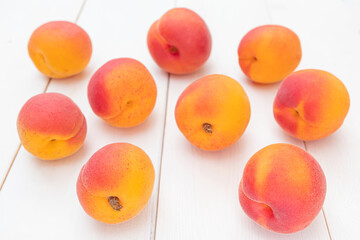 Ripe bright apricots lie on a white wooden surface. Summer fruit harvest.