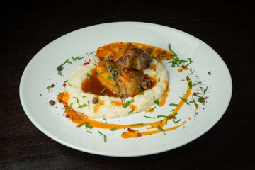 Duck leg with mashed potatoes.On a white plate. On black background