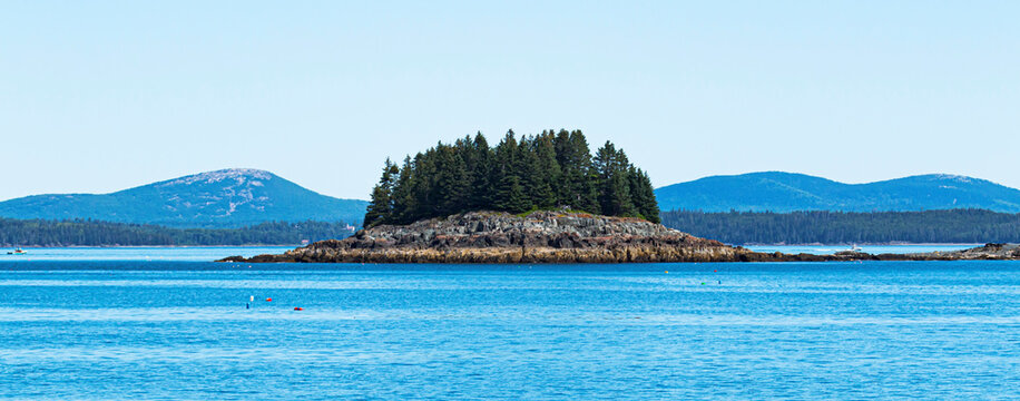 Small island with tall evergreens in waters of Bar Harbor Maine USA