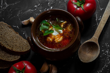 borsch in a clay pot with sour cream, brown bread and fresh herbs