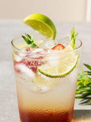 refreshing summer cocktail drink lemonade with ice,  lime, strawberries and tarragon in a glass close up
