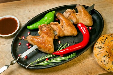 Grilled chicken wings with hot pepper . With barbecue sauce and fresh tortilla. On a wooden tray