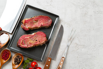 Marinated raw steaks on stone table with spices