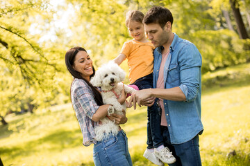 Happy family with cute bichon dog in the park
