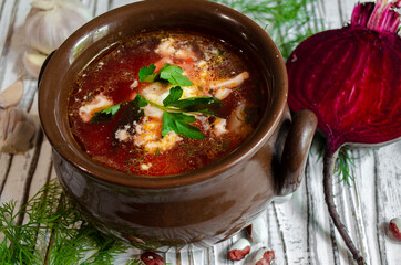 borsch in a clay pot with sour cream, brown bread and fresh herbs