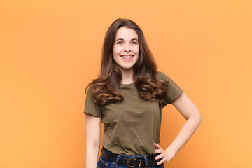 young pretty woman smiling happily with a hand on hip and confident, positive, proud and friendly...