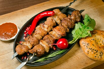 Assorted beef and pork kebabs with red pepper and radish. With barbecue sauce and fresh tortilla. On a wooden tray
