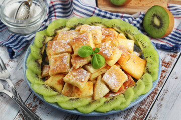 Austrian dessert Kaiserschmarrn served with sugar powder and kiwi fruit