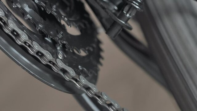 Closeup of chain rings on mountain bike MTB. Work of chain drive chainset. Gearshift, changes speeds. Shift gears on bicycle crank. Front derailleur. Macro low angle shot. Wheel spins and turns