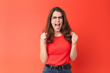 young pretty woman feeling shocked, excited and happy, laughing and celebrating success, saying...