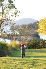 A child playing outside with a soccer ball on a grassy field during a break while home schooling in the Gulf Islands of Canada.