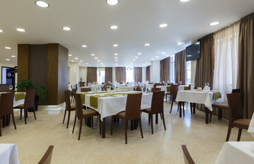 Tables in hotel restaurant with wooden chairs