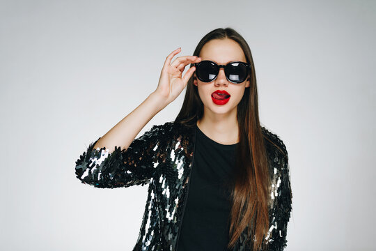 Fashionable modern woman in a black shiny jacket and black glasses