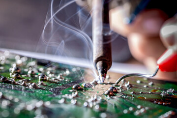 Technician repair electronic circuit board with soldering iron and tin wire