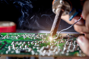 Technician repair electronic circuit board with soldering iron and tin wire