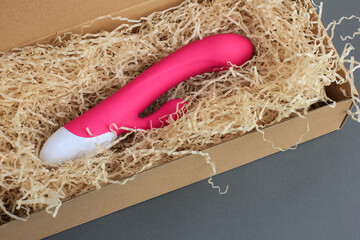 Sex toy for adult, design pink dildo vibrator lying in an open craft box as a gift. Concept of sex,...