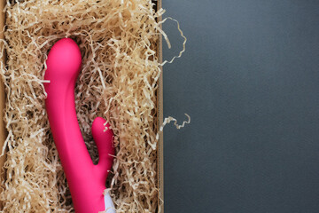Sex toy for adult, design pink dildo vibrator lying in an open craft box as a gift. Concept of sex,...