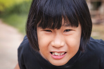 Obraz premium Portrait, Face of little Asian girl smiling outdoors at park, close-up
