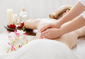 Spa day. Girl receives massage on table with flowers and oil