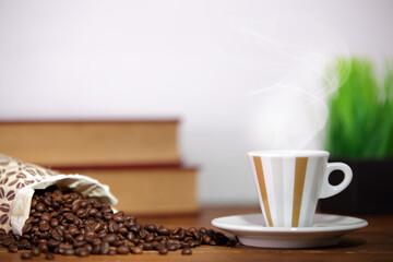 Tazza di caffè caldo e chicchi di caffè su un piano in legno