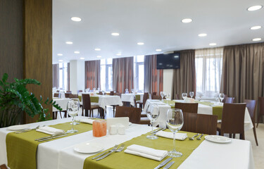Tableware in hotel restaurant. Room with luminous lit