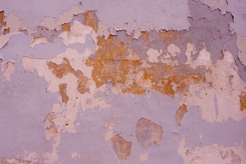Old wall with several layers of peeling paint. Purple and lilac colours
