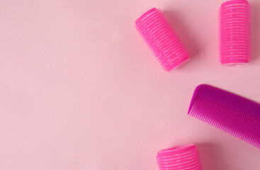 Hairdressing services-banner-comb and curlers on a pink background, place for the inscription, top view.