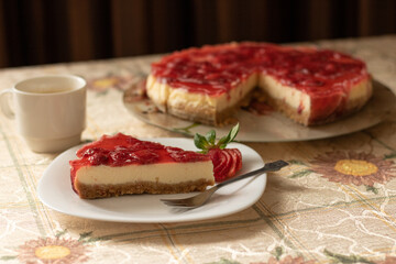 New York Cheesecake with Strawberries in a white plate on a tablecloth, fork and tray, homemade