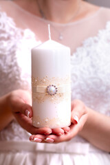 bride holds a wedding candle in her hands