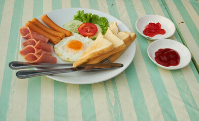 Breakfast set with eggs, sausages, toasts and fresh vegetable, top with tomato, include tomato sauce