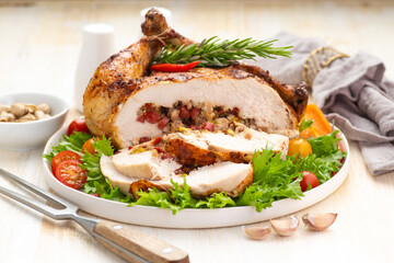 Stuffed boneless chicken garnished with fresh vegetables, lettuce, cherry tomatoes, bell peppers and fresh rosemary herbs