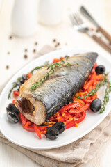 Baked fish mackerel with vegetables, sweet pepper and black olives and herbs.