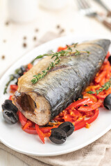Baked fish mackerel with vegetables, sweet pepper and black olives and herbs.
