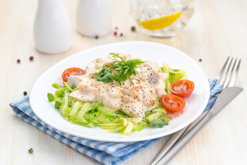 Salmon slices in creamy sauces and zucchini. Ketogenic food.