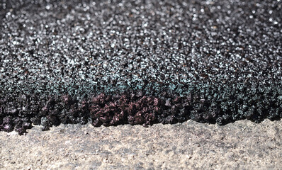 Road repair and thin layer of new asphalt close-up.