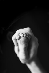 A father holds the tiny foot of his newborn son.
