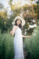 Fototapeta na wymiar Young beautiful woman in a white dress posing in white flower garden