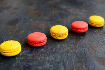 Red and yellow macaroons in a line on a dark blue background.